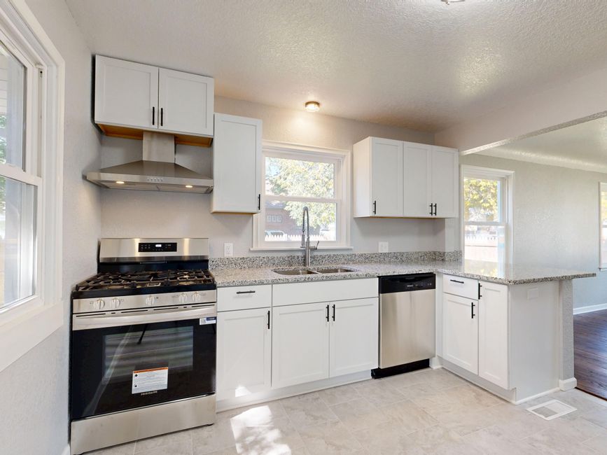 Bright modern kitchen featuring white cabinets and stainless steel appliances.